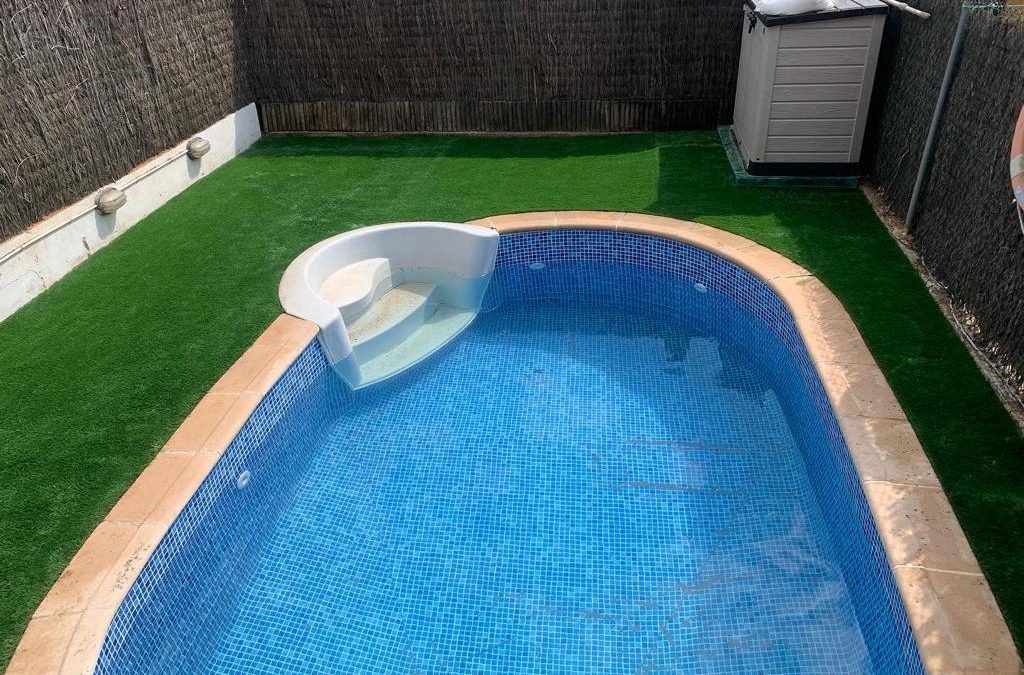 Piscina exterior rodeada de césped artificial en jardín privado