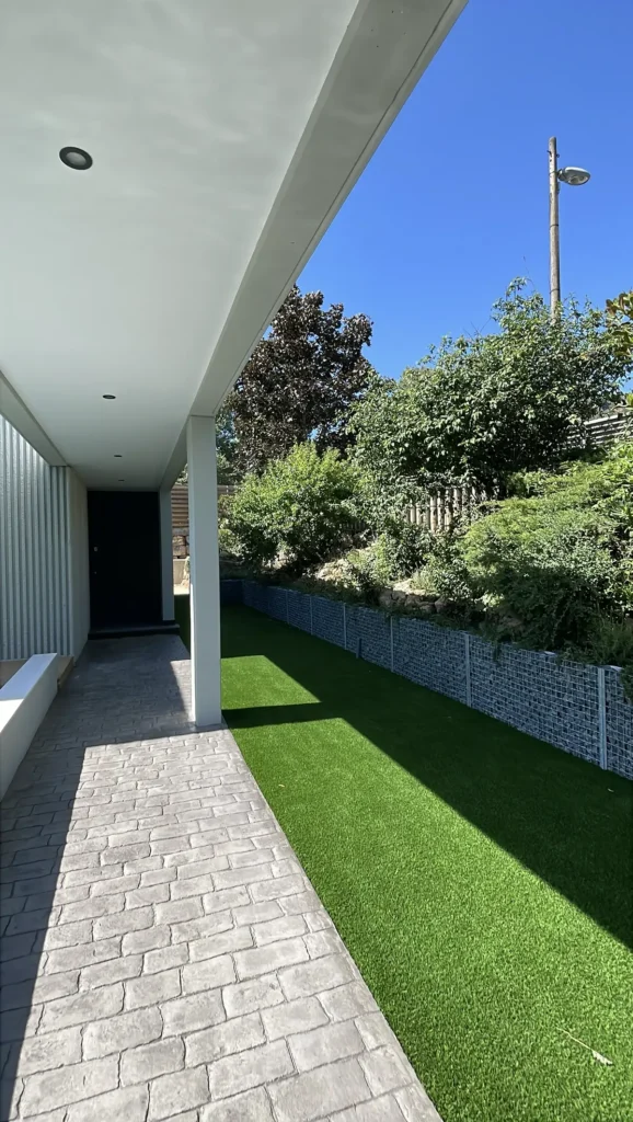Detalle de la instalación de césped artificial junto a una vivienda moderna