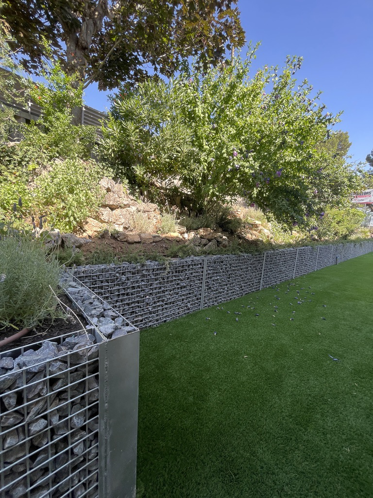 Jardín con gaviones, césped artificial y vegetación mediterránea
