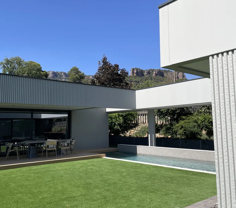 Jardín moderno con césped, piscina y paisajismo realizado por Serveis Jardineria Soler